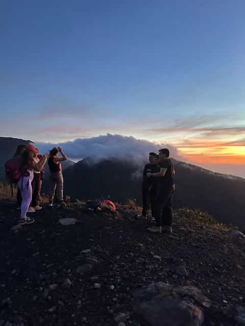 Friends watching the sunrise above the clouds on the Izalco volcano