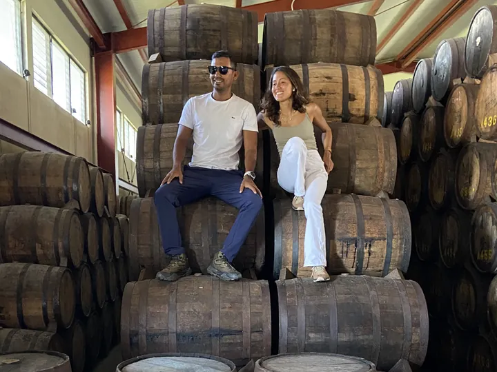 Two travelers sitting on stacked rum barrels at the Cihuatán distillery