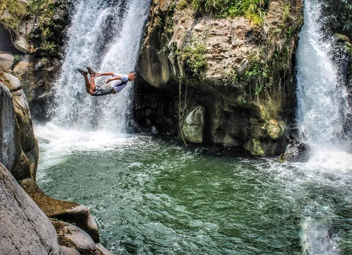A traveler jumping into the pool of a waterfall in Tamanique, El Salvador